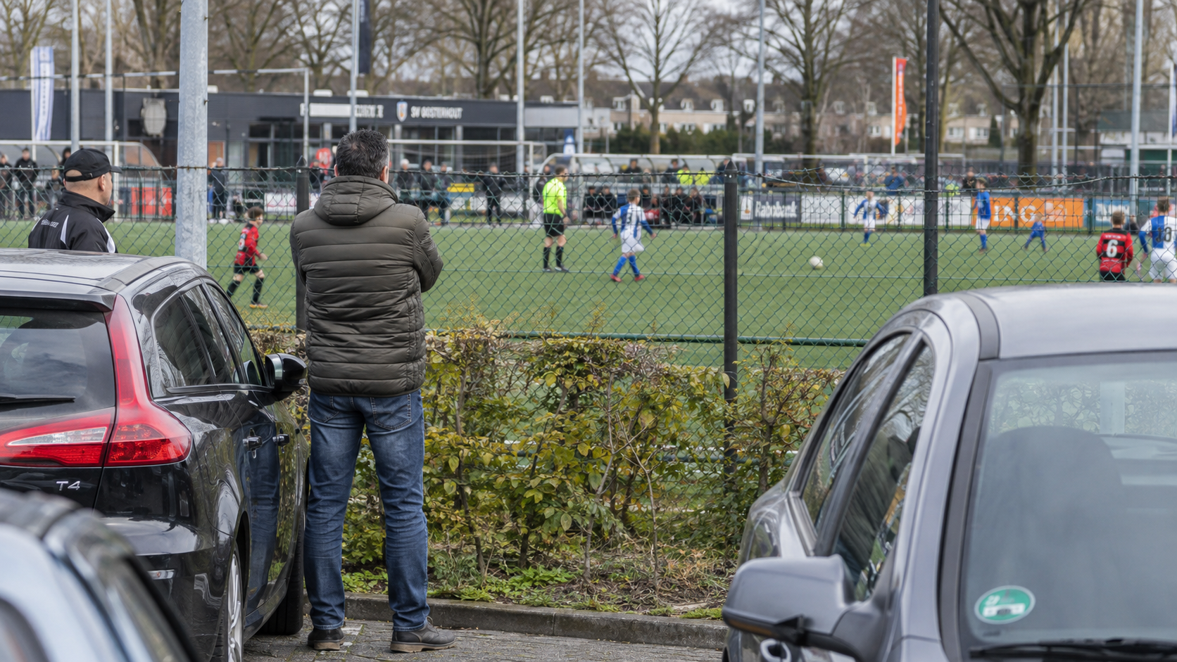 Scheidsrechter toont een zwarte kaart aan toeschouwers langs een jeugdvoetbalveld.